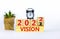 2022 vision new year symbol. Alarm clock. Turned a wooden cube, changed words `vision 2021` to `vision 2022`. Beautiful white