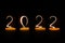 2022 written with candle flames on black background new year greeting card