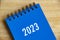2023 blue desk calendar on wooden table background.