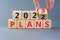 2023 plans new year symbol. Businessman turns a wooden cube and changes words Plans 2022 to Plans 2023. Beautiful grey table grey