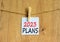 2023 Plans symbol. White paper with words 2023 Plans, clip on wooden clothespin. Beautiful wooden background. Business and 2023