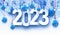 2023 sign in with blue hanging baubles, white fir tree branches and snow