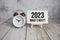 2023 What`s Next? text message and alarm clock on wooden background