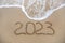 2023 year written on sandy beach sea. Top view. Flat lay