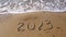 2023 year written on sandy beach sea. Top view. Flat lay