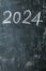 2024 date handwritten in a chalk writing text script on a wooden black chalkboard