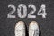 2024 Goals Concept. Human legs and shoes on asphalt background