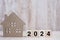 2024 Happy New Year with house model on table wooden background. Banking, real estate, investment, financial, savings and New Year