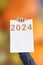 2024, Man holding cardboard with number 2024 on orange background. Happy New Year
