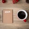 2024 notebook, black coffee cup and Christmas gift on wood table, Top view and copy space. Xmas, Happy New Year, Goals, Resolution