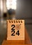2024 numbers year with target icon on beige small desk calendar cover standing on wood table, vertical, minimal style.