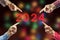 2024, People pointing to the number 2024 on background of faded lights. Happy New Year