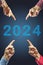 2024, People pointing to the number 2024 on blue background. Happy New Year