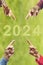 2024, People pointing to the number 2024 on green background. Happy New Year