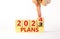 2024 plans new year symbol. Businessman turns a wooden cube and changes words Plans 2023 to Plans 2024. Beautiful white table