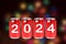 2024, Red soda cans with the number 2024 on background of faded lights. Happy New Year