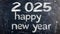 2025 Happy New Year date handwritten in a chalk writing text script on a wooden black chalkboard