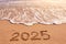 2025 year written on sandy beach sea at sunny day
