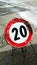 20km speed limit construction site sign, damaged by time on asphalt
