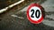 20km speed limit construction site sign, damaged by time on asphalt seen