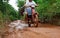 28 DECEMBER 2016, Vietnam, Can Txo. Dirt mud road in jungle of Vietnam after rain, two people on motorbike