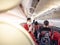28 jun 20, Donmueng Airport, Bangkok, Thailand. Female cabin crew in red uniform greeting passenger in aircraft cabin during board