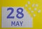 28 may calendar date on a white puzzle with separate details. Puzzle on a yellow background with a blue inscription