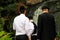 3 boys, a family of Hasidic Jews, in traditional clothes  stand in front of a waterfall in the park in Uman, Ukraine