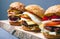 3 different burgers on a wooden shelf. fresh homemade cheeseburger on gray background