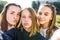 3 girls girlfriends teenagers, 14-15 years old, taking selfie photo on telephone camera, on autumn day in city on street