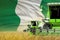 3 green modern combine harvesters with Nigeria flag on rural field - close view, farming concept - industrial 3D illustration