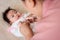 3-month-old Asian newborn girl is laying in bed happily. and her mother leaned in for comfort and play. A girl who had just given