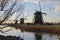 3 Old dutch windmills in the countryside with birds