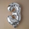 3 three metallic balloon on beige neutral background. Greeting card silver foil balloon number Happy birthday holiday