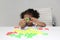 3-year-old Latina girl with brunette and curly hair plays with a game of letters and numbers for learning within the autism