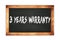 3  YEARS  WARRANTY text written on wooden frame school blackboard