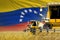 3 yellow modern combine harvesters with Venezuela flag on rye field - close view, farming concept - industrial 3D illustration