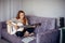 30 woman playing the guitar, sitting on the sofa in home interior. Lovely young girl learning to play the guitar with music sheets