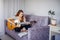 30 woman playing the guitar, sitting on the sofa in home interior. Lovely young girl learning to play the guitar with music sheets