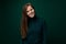 30 year old friendly European woman wearing a green turtleneck on a dark background