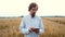 30-year-old stylish male agronomist with a beard walks across the field and writes data to a tablet. Harvest inspection
