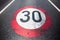 30km/h speed limit sign painted on asphalting road.