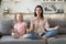 30s woman sitting in lotus pose with cute little daughter.