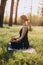 A 36-year-old young woman practices yoga on an morning in the woods among the trees in the lotus position. Healthy lifestyle