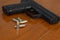 .38 mm handgun and bullets strewn on the rustic wooden table background. Gun with ammunition and  ammo or 9mm handgun on