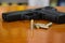.38 mm handgun and bullets strewn on the rustic wooden table background. Gun with ammunition and  ammo or 9mm handgun on
