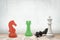 3d close-up rendering of four chess pieces: red knight, green rook and white king standing, and black king lying on