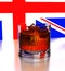 3d. Cubes of ice fall into a glass with whiskey. The background is a fragment of the English flag. Splash, shadow, reflection