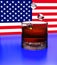 3d. Cubes of ice fall into a glass with whiskey. The background is a fragment of the USA flag. Splash, shadow, reflection