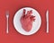 3d illustration of anatomical heart on plate, knife and fork. Concept of toxic relationship, heartbreak